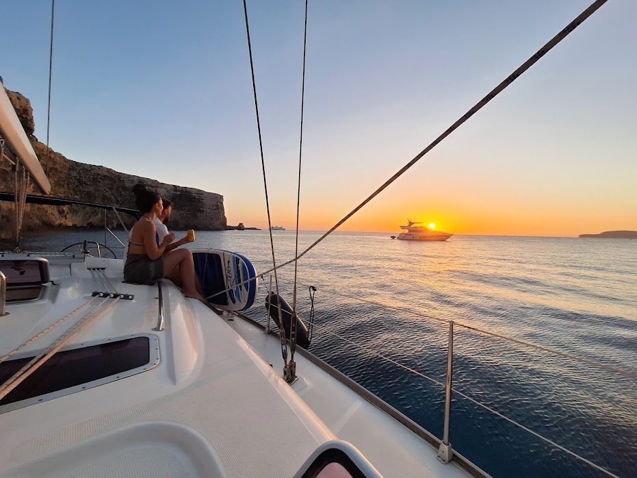 Couple drinking on a boat, watching the sunset over the sea.